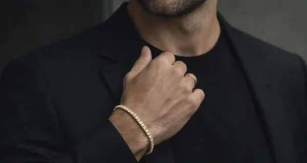 Hombre con pulsera rivière de diamantes en oro amarillo combinada con un traje oscuro