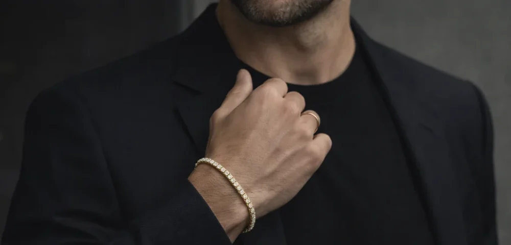 Hombre con pulsera rivière de diamantes en oro amarillo combinada con un traje oscuro